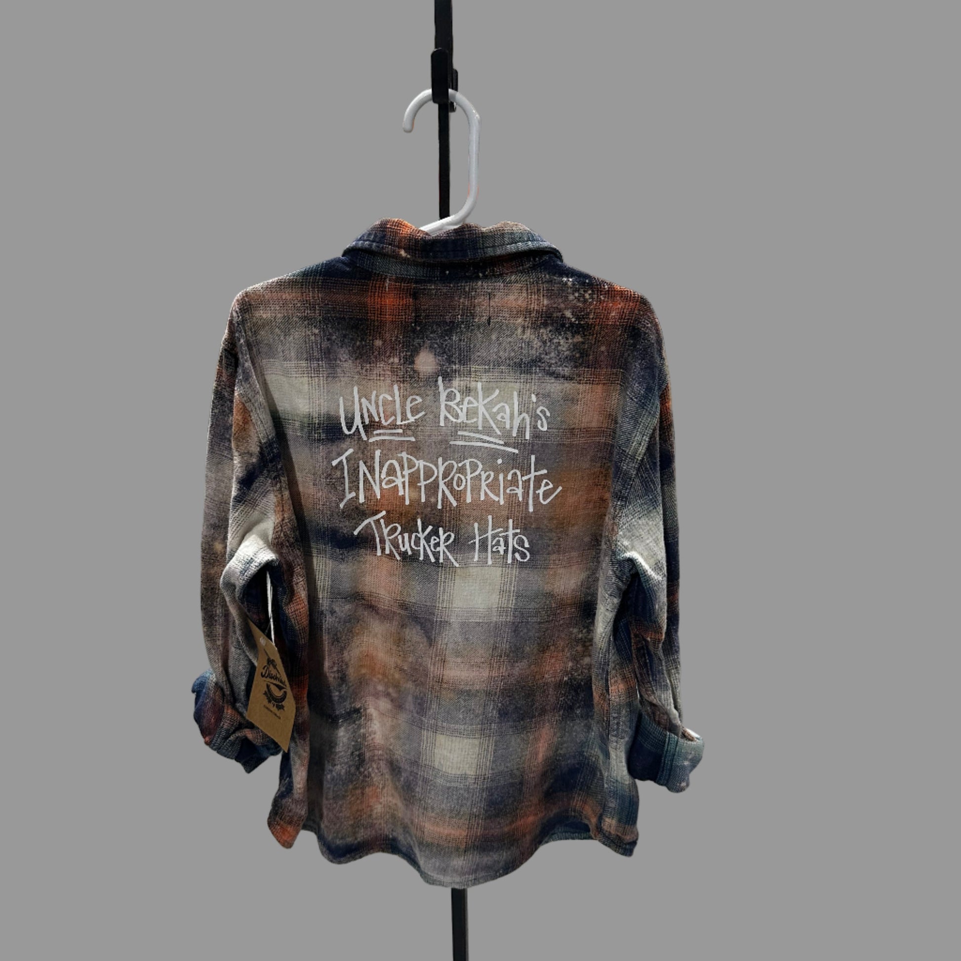 Plaid shirt with text on a stand in a room with various items on shelves.