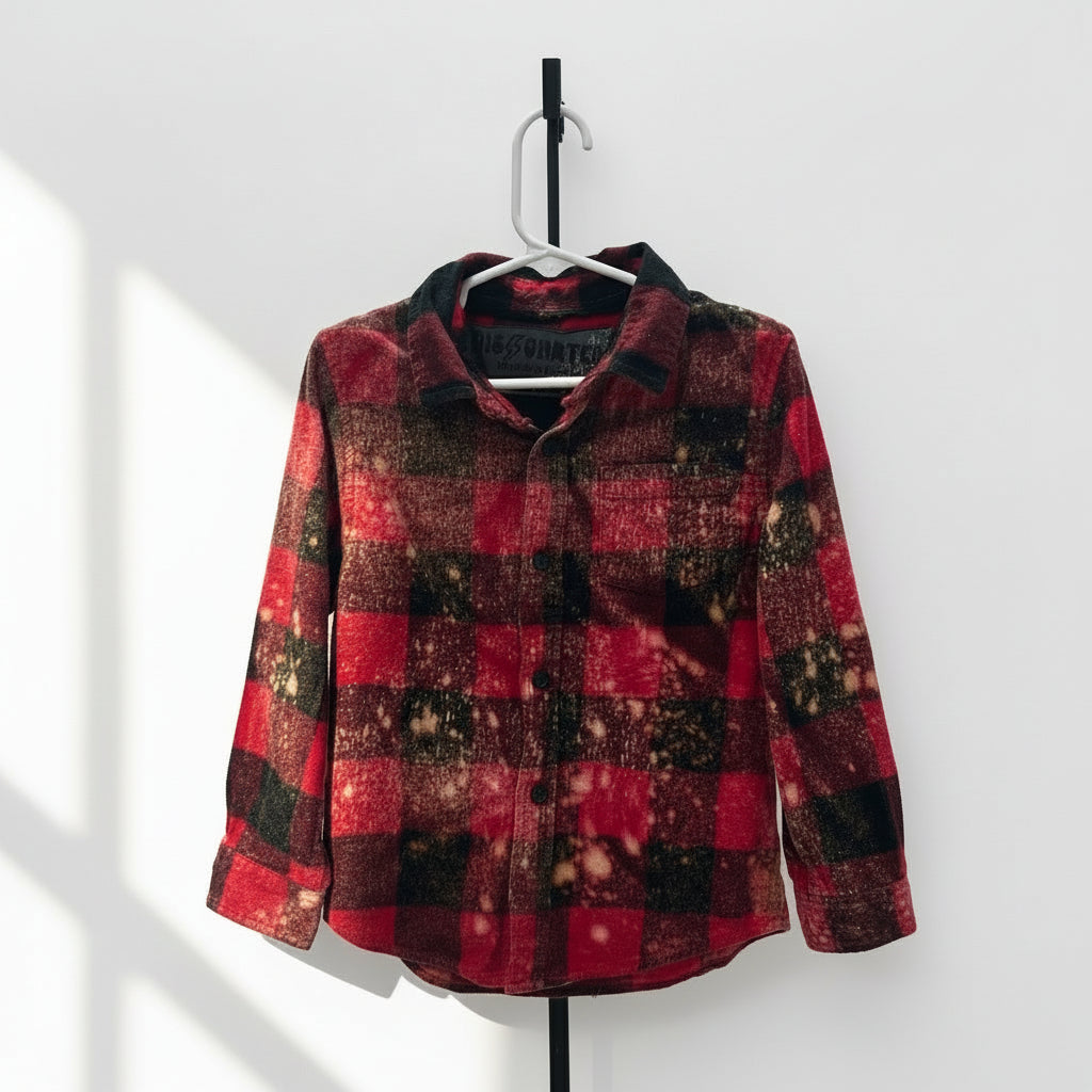 Red and black checkered jacket on a mannequin against a white brick wall.